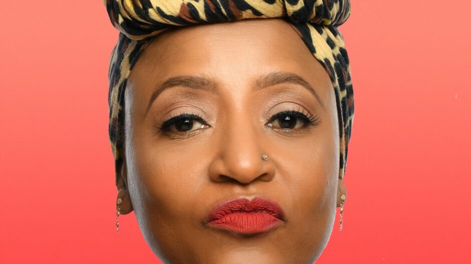 A headshot of author and comedian Njambi McGrath, she is wearing a leopard print head scarf and red lipstick and it looking directly in to the camera